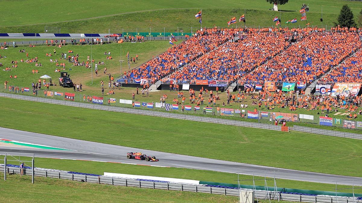 Race car on the tracks in front of a crowd wearing orange shirts