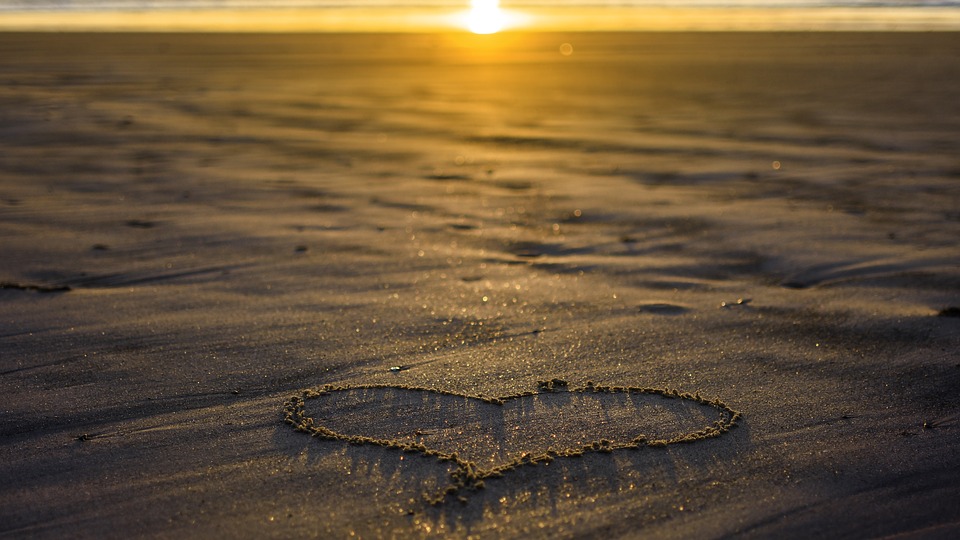 heart in sand, low sun in the background