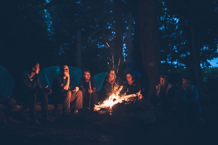 People around a lit campfire in the evening