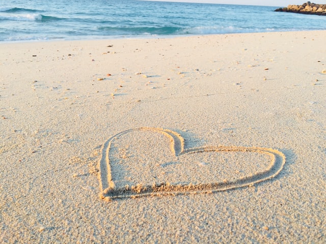 heart shape in the sand with the sea in front
