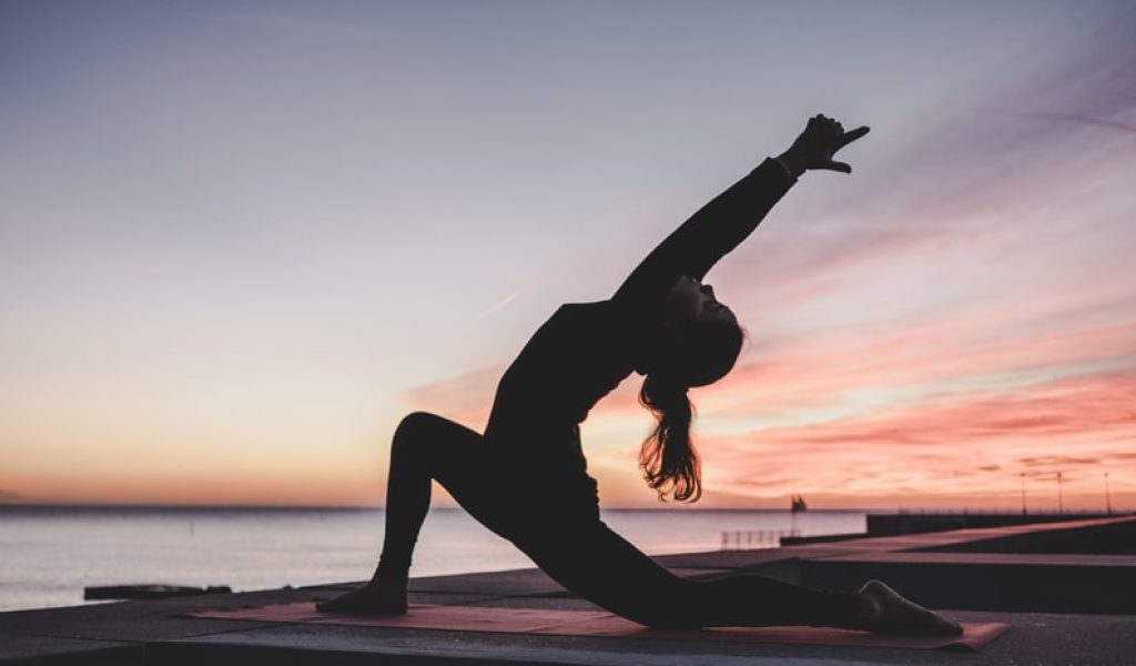 Person doing yoga at sunset