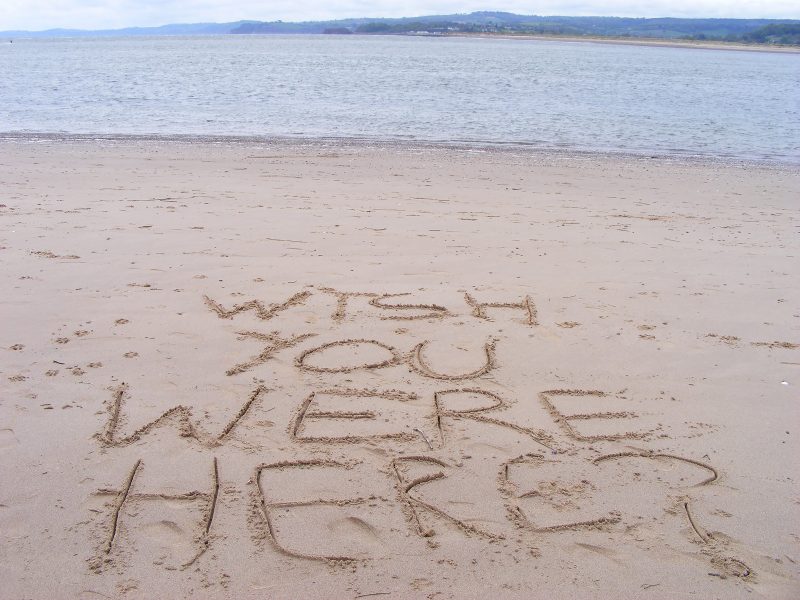 'Wish You Were Here?' written on a beach